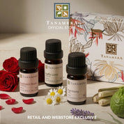 Tanamera essential oil bottles with packaging and flowers on a wooden surface